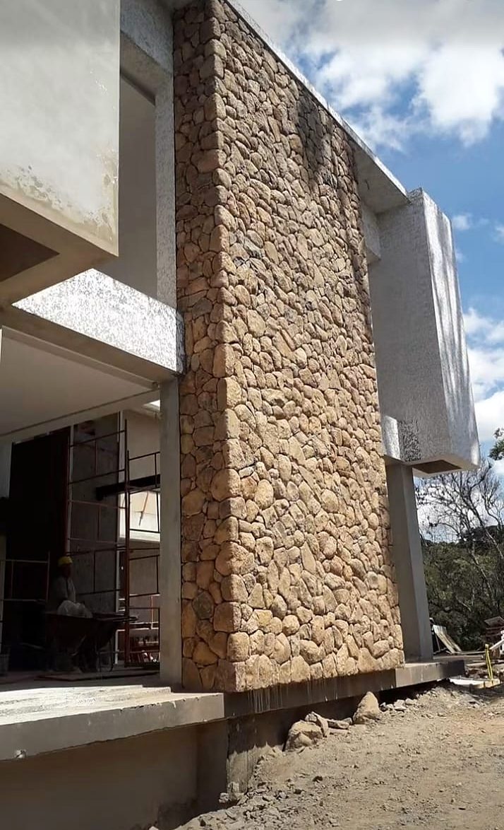 Fachada de residência com parede revestida em pedra, durante a obra