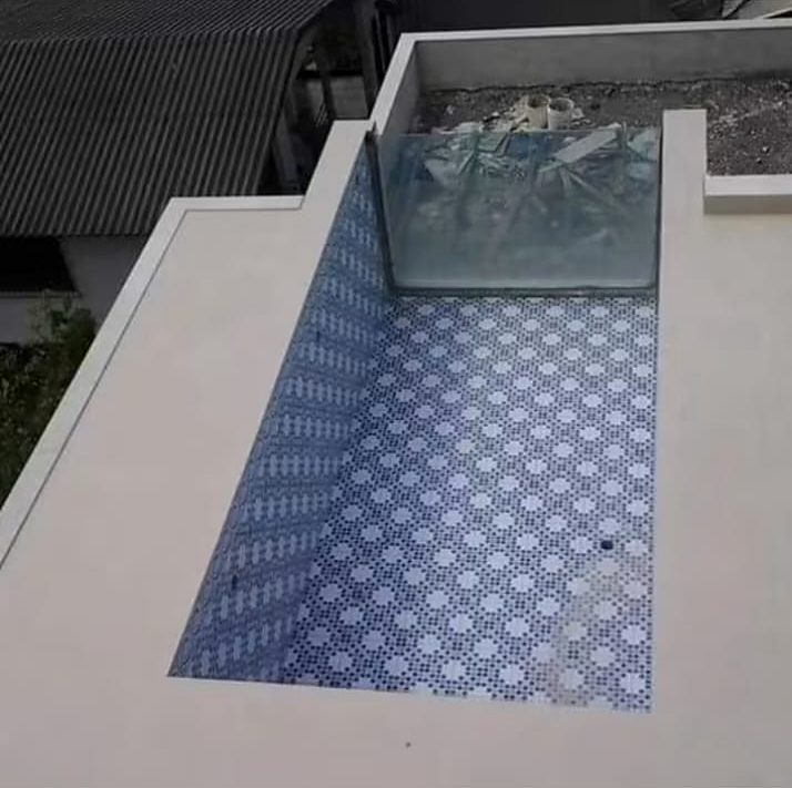 Piscina revestida com pastilhas azuis e guarda-corpo de vidro